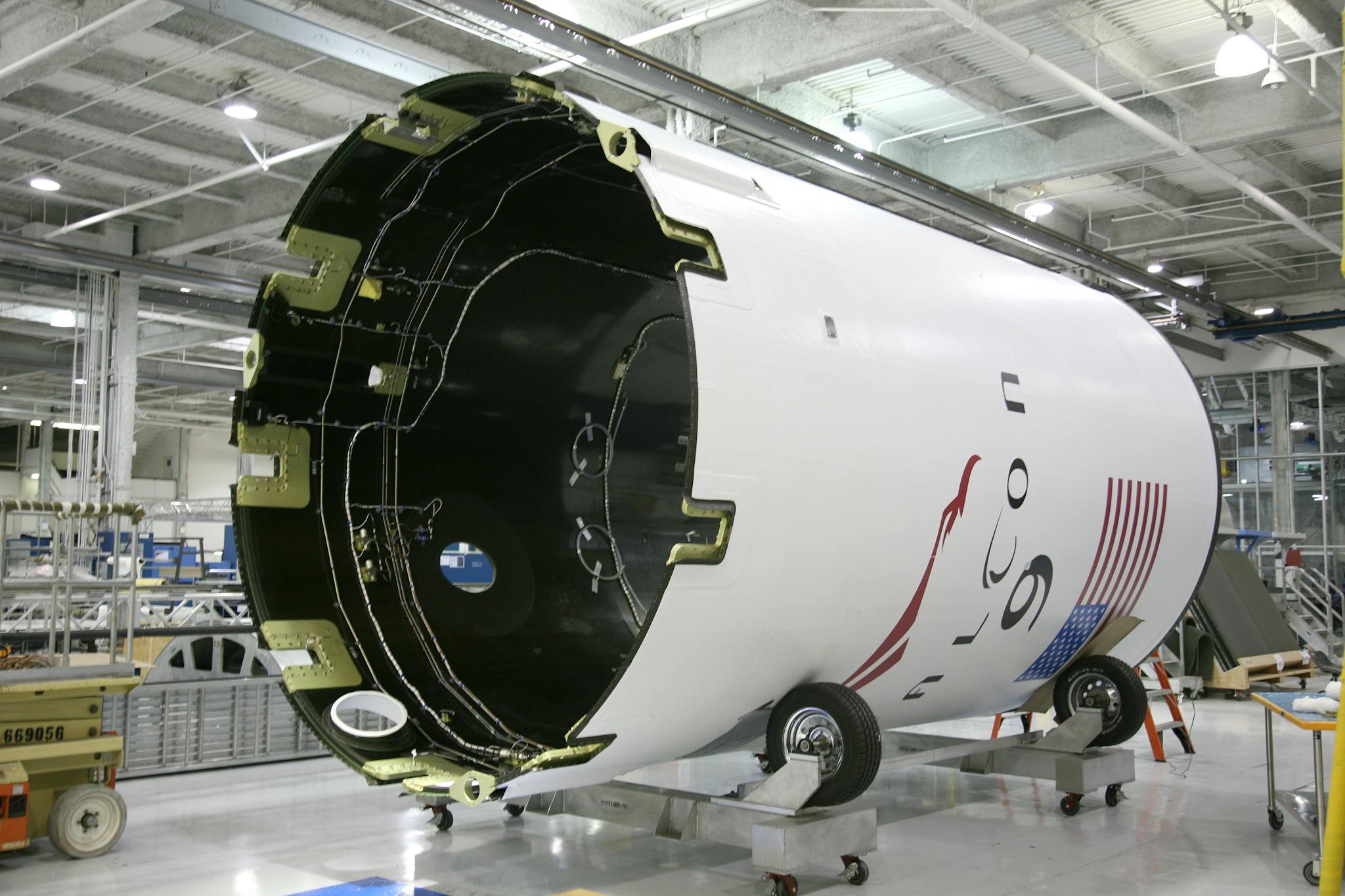 From below of exterior detail of rocket with inscription and American flag placed on rolling platform at modern factory