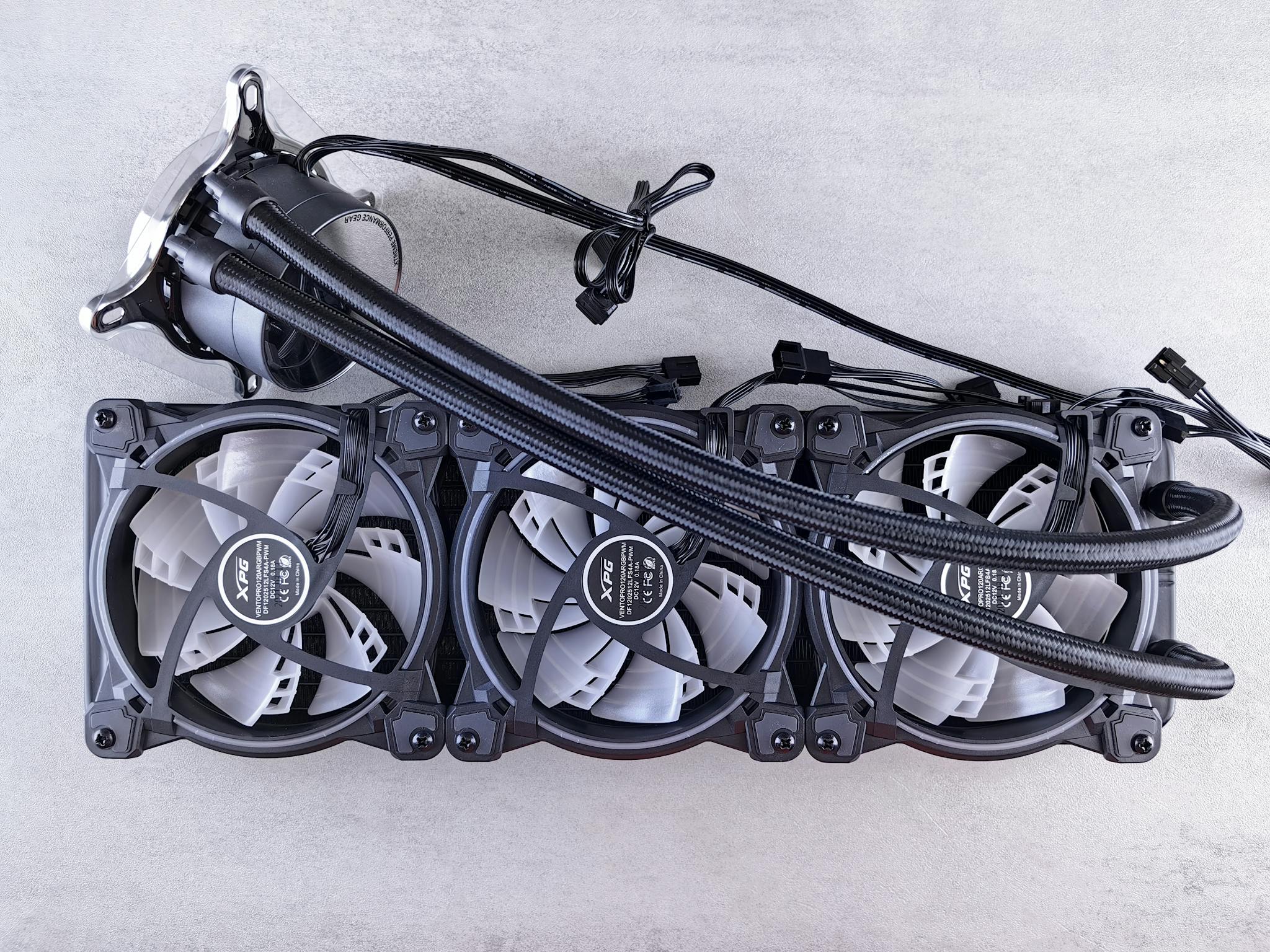 Top view of a triple radiator cooling system with fans for computer hardware in a minimalist gray setting.